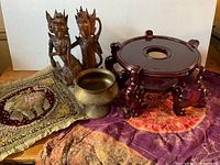 Group shot showing wood sculpture, brass bowl, plant stand, elephant textile, silk fabric