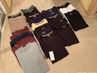 All 20 folded Duluth Trading T-shirts laid out on carpet