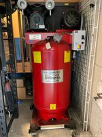 Front view of red Eaton vertical air compressor on rolling stand showing pump, motor and control box