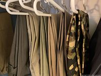 Seven pairs Duluth Trading pants hanging, khaki and one camo visible