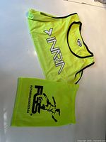 Both fluorescent yellow mesh pinnies laid flat, showing INRIA logo on one and FSS logo with soccer graphic on the other