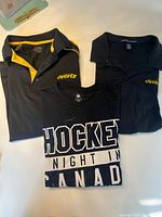 All three shirts laid flat: two Evertz polos and one Hockey Night In Canada T-shirt