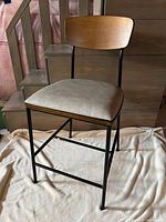 Full view of bar stool showing wood backrest, upholstered seat, metal frame