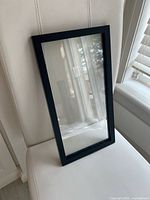 Front view of black rectangular floating picture frame against chair