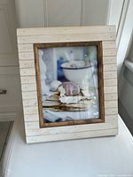 Front view of whitewashed slat wood picture frame with brown inner border