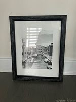 Full view of black picture frame with white mat and black-and-white canal photograph