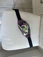 Front view showing patterned pouch with retail insert and adjustable strap