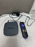 Roku 4630X unit, voice remote, and power adapter laid out on surface
