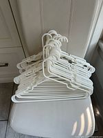 Stack of white plastic hangers showing full quantity and style