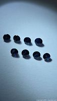 Eight round deep blue sapphires on white background