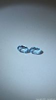 Pair of oval sky blue topaz gemstones on neutral background