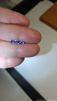 Four small cushion cut deep blue tanzanite stones on fingertip