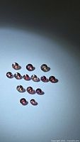 Group of small round faceted sapphires in varied pink and orangish tones