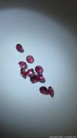 Nine pink-purple faceted garnets on white background