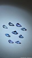 Nine pear-cut tanzanite gemstones in overhead lighting