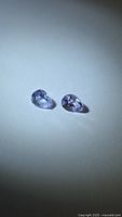 Two pear-cut lavender tanzanites on white background
