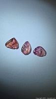 Three pink tourmaline leaf-cut stones on neutral background