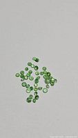 Group of small round green tsavorite garnets on neutral background