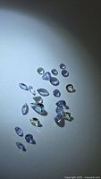 Group of loose mixed-cut tanzanite gemstones under spotlight