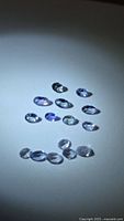 All loose tanzanite gemstones arranged on white surface