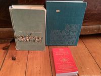 Three books standing and lying on floor showing covers: Medical-Surgical Nursing, Roen Atlas of Urologic Surgery, Dictionary of Medical Terms