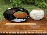 Black Toyo ikebana vase and white ribbed planter beside ruler for scale