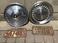 Two hubcaps and two license plates on pavement