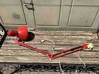 Full view red adjustable lamp extended on bench