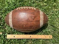 Side view showing Spalding J5V Canadian Football League logo and commissioner stamp with ruler for scale
