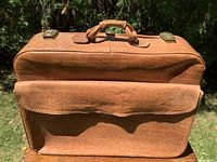 Front view showing leather body, handle, brass locks, front flap pocket