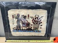 Overall view of framed papyrus art, tape for width measurement