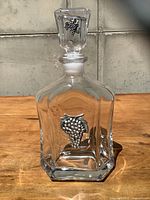 Front view of clear crystal decanter with pewter grape motif