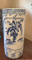 Full view of cylindrical ceramic umbrella stand showing bamboo and boat scene