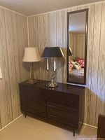 Dresser with two brass lamps and mirror against paneled wall