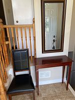 Console table, leather chair and framed mirror in entryway setting