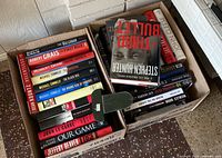 Two cartons filled with hardcover novels; spines and some covers visible