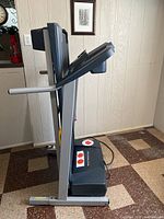 side view of folded treadmill showing frame, console, rails