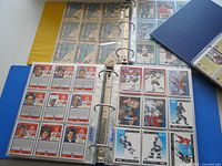 Open binders showing pages of hockey cards front and back views