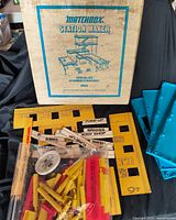 Box front and assorted blue base plates, yellow/red structural parts, signage sheets visible