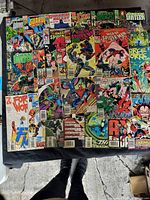 Overhead view of 25 comic books laid out on table showing covers