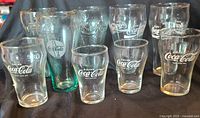 Ten assorted Coca-Cola branded glasses, various shapes and logo styles