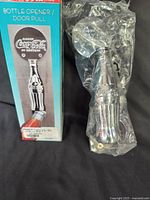 Box showing product image and text "Bottle Opener / Door Pull" beside the chrome metal opener sealed in plastic