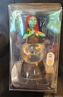 Front view of sealed Sally musical glitter globe in plastic packaging showing Try Me button
