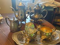 Group shot of coffee pot, teapot, small pot, sugar, creamer, candlestick and tray