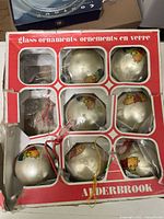 Front view of box showing seven champagne glass ornaments with Pooh decals and mismatched strings
