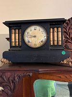 Front view of black wood mantel clock on cabinet