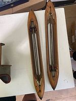Two vintage wooden weaving shuttles on white table, top view shows overall design and wear