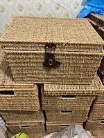 Stack of woven baskets, top basket shows leather-look strap latch, cutout handles visible
