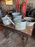 All four galvanized containers on table showing relative sizes and patina