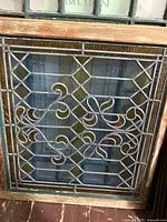 Front view of first stained glass panel showing multicolor panes, scroll design, wood frame